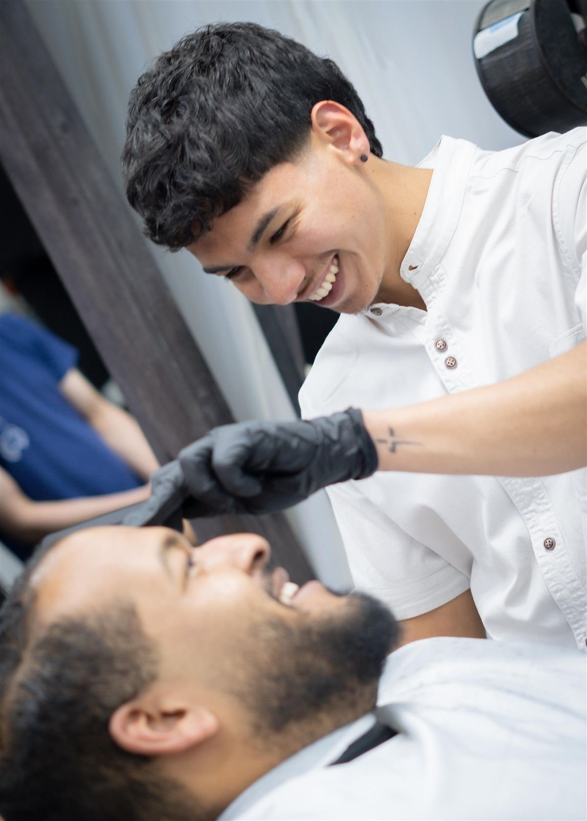 Barbero de Clase A atendiendo a un cliente con una sonrisa